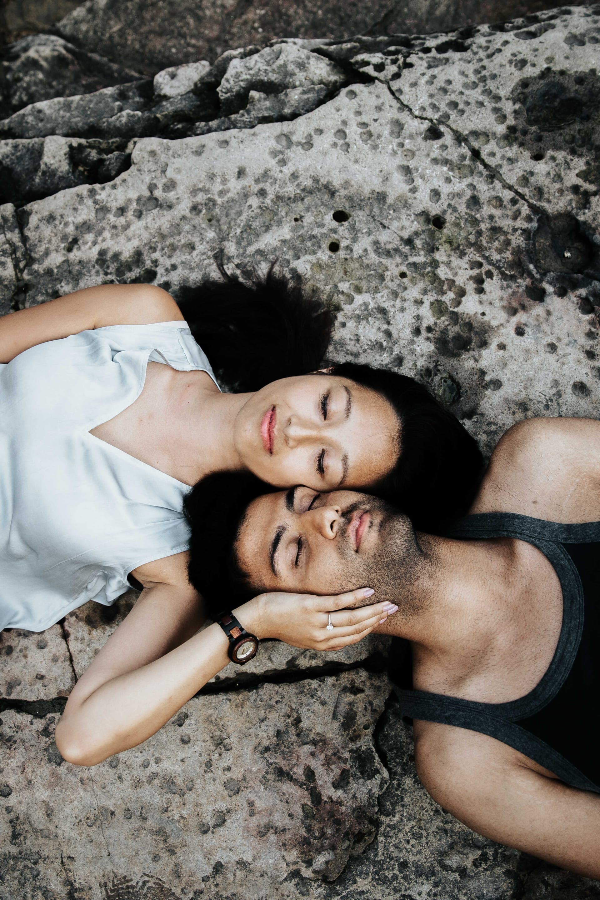 Amir and Samantha lying head to head on a rock beside the water
