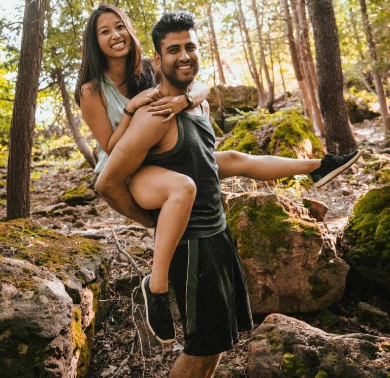 Amir Khela carrying Samantha Khela piggyback on a mossy forest trail